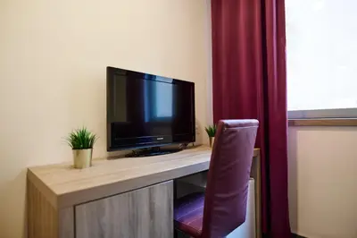 a television sitting on top of a desk with a chair at Hotel Meksiko in Ljubljana
