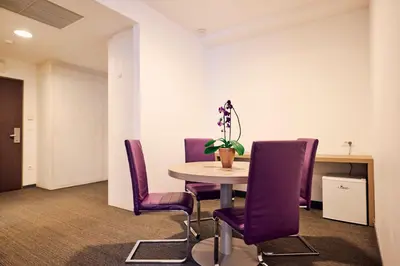 a conference room with a table and purple chairs at Hotel Meksiko in Ljubljana