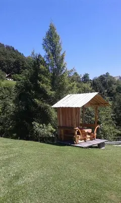 a wooden gazebo in the middle of a grass field at Apartments Za Grapo in Cerkno