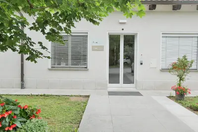 a front door of a white house with red flowers at Prenočišča Kogoj in Miren