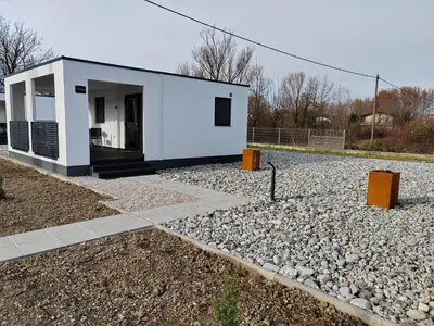 a small white building on a gravel road at Prenočišča Kogoj in Miren