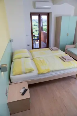 a large bed with yellow pillows and a table at Zoi Apartments in Dobrovo