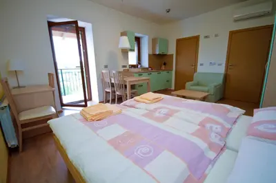 a bedroom with a large bed and a kitchen at Zoi Apartments in Dobrovo