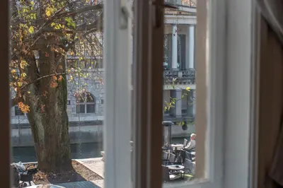a window with a view of a man sitting at a table at River View Apartment in Ljubljana