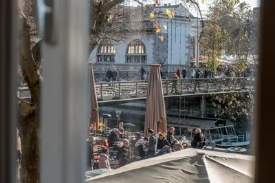 a group of people sitting at tables with umbrellas at River View Apartment in Ljubljana