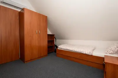 a bedroom with two beds and wooden cabinets at Apartmajske hiške Lubadarček in Podčetrtek