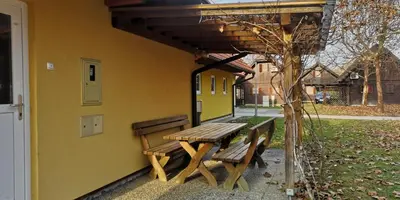 a picnic table and benches on the side of a building at Apartmajske hiške Lubadarček in Podčetrtek