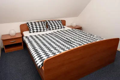 a bed with a black and white checkered blanket at Apartmajske hiške Lubadarček in Podčetrtek