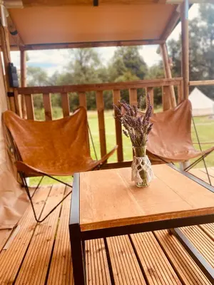 a vase of flowers sitting on a table on a deck at GreenValleyGlamping in Šešče pri Preboldu
