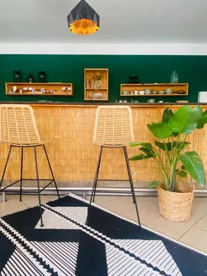 two chairs in front of a bar with a plant at GreenValleyGlamping in Šešče pri Preboldu