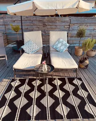 a patio with two chairs and a table and an umbrella at GreenValleyGlamping in Šešče pri Preboldu