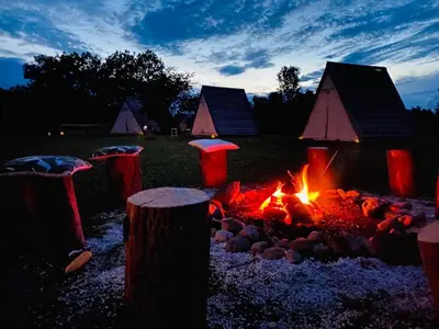 a fire pit in front of a group of tents at GreenValleyGlamping in Šešče pri Preboldu