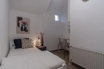 a bedroom with two beds and a desk at Apartments Park Šiška Ljubljana in Ljubljana