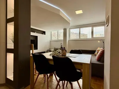 a dining room and living room with a table and chairs at Apartments Park Šiška Ljubljana in Ljubljana