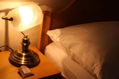 a lamp on a table next to a bed at B&B Pod Skalo in Kamnik