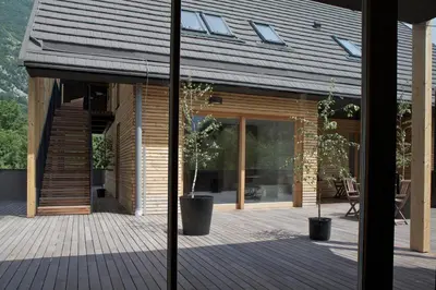 a house with a wooden deck with two potted plants at Hotel Sanje ob Soči ***/**** in Bovec