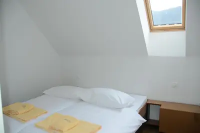 a bed with two towels on it with a window at Hotel Sanje ob Soči ***/**** in Bovec