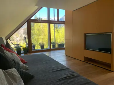 a living room with a tv and a large window at Hotel Sanje ob Soči ***/**** in Bovec