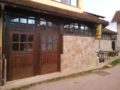a garage with wooden doors and a stone wall at Gostilna Ulčar in Ig
