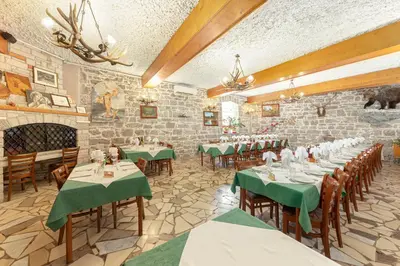 a dining room with tables and chairs and a brick wall at Guest House Pod Slavnikom in Podgorje