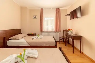 a hotel room with two beds and a desk at Guest House Pod Slavnikom in Podgorje