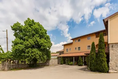 a building with a tree and a stone wall at Guest House Pod Slavnikom in Podgorje