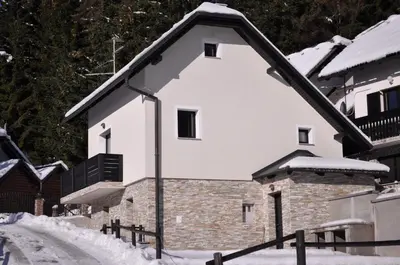 a white building with a snow covered roof at Holiday house Nune in Zreče