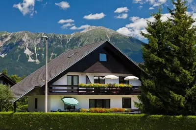 a house with a balcony with flowers in front of a mountain at Lake Bled Apartment Marjetka in Bled