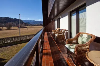 a balcony with wicker chairs and tables on a building at Lake Bled Apartment Marjetka in Bled