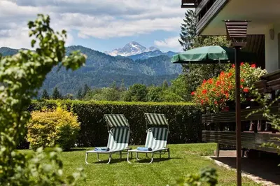 two chairs and an umbrella in a yard with a mountain at Lake Bled Apartment Marjetka in Bled