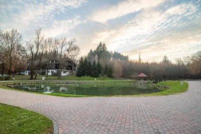 a pond in a park with a house and trees at Apartment Amy in Podčetrtek