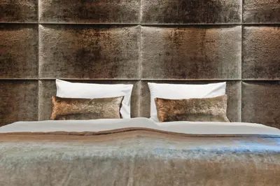 a bed with four pillows in front of a wall at G Design Hotel in Ljubljana
