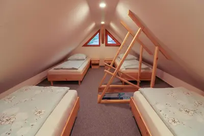 a attic room with two beds and a window at Apartments & Rooms Pr' Skalovc in Bohinj
