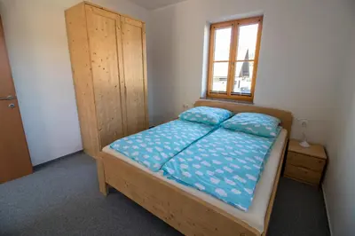 a bedroom with a bed with blue sheets and a window at Apartments & Rooms Pr' Skalovc in Bohinj