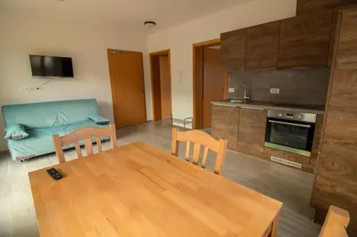 a living room with a table and a kitchen at Apartments & Rooms Pr' Skalovc in Bohinj