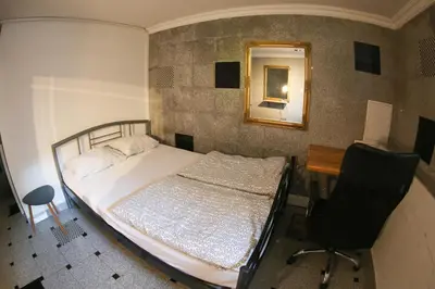 a bedroom with a bed and a desk and a mirror at Hostel 24 in Ljubljana