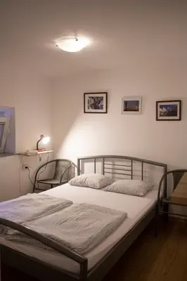 a bed in a bedroom with two chairs at Hostel 24 in Ljubljana