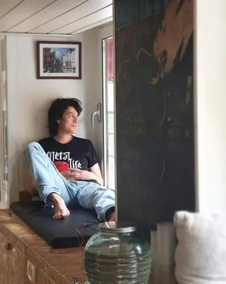 a man sitting on a bed looking at himself in a mirror at Hostel 24 in Ljubljana