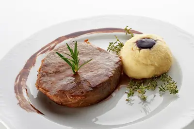 a white plate with a piece of meat and a cookie at Grobelnik Tourist Farm in Sevnica