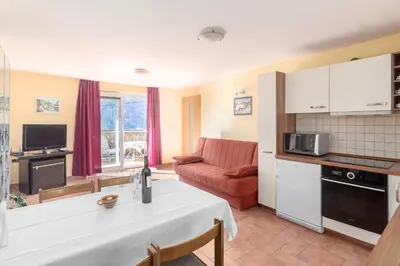a kitchen and living room with a table and a couch at Apartment house Jager in Bohinj