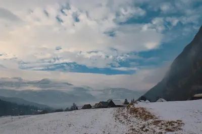 a snow covered hill with houses and mountains at Apartment house Jager in Bohinj
