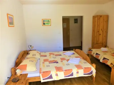 a bedroom with two beds and a wooden table at Pension Na Meji in Pivka
