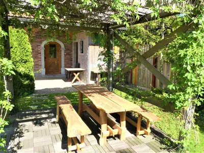 a wooden picnic table and benches in a garden at Pension Na Meji in Pivka