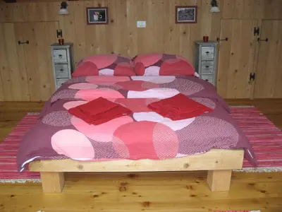 a bedroom with a large bed with red pillows at Pension Na Meji in Pivka