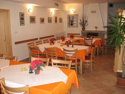 a restaurant with tables and chairs with orange table cloth at Pension Na Meji in Pivka