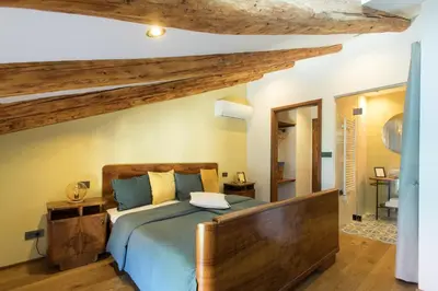 a bedroom with a large bed with a wooden headboard at Špacapanova hiša in Komen