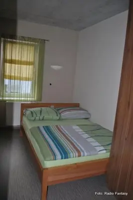 a bed with a wooden frame in a bedroom at Hostel Plus Caffe in Petrovče