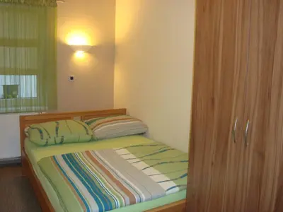a bedroom with a bed and a wooden cabinet at Hostel Plus Caffe in Petrovče