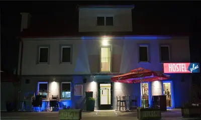 a house with a red umbrella and a building at Hostel Plus Caffe in Petrovče