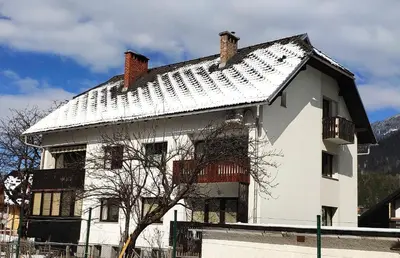 a white house with a snow covered roof at Cozy Nest in the heart of Kranjska Gora in Kranjska Gora